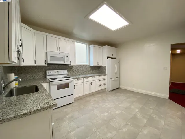 a kitchen with granite countertop a sink a stove and cabinets