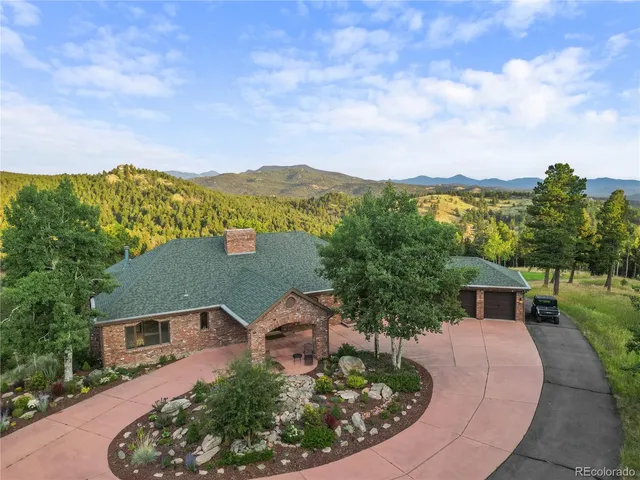 an aerial view of a house with a garden and mountains