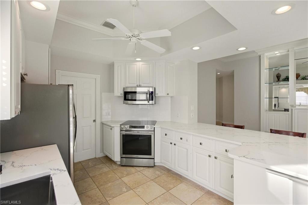 7704 Hernando Court Naples, FL 34114 - Photo 9 of 41 a kitchen with stainless steel appliances kitchen island granite countertop a refrigerator sink and stove