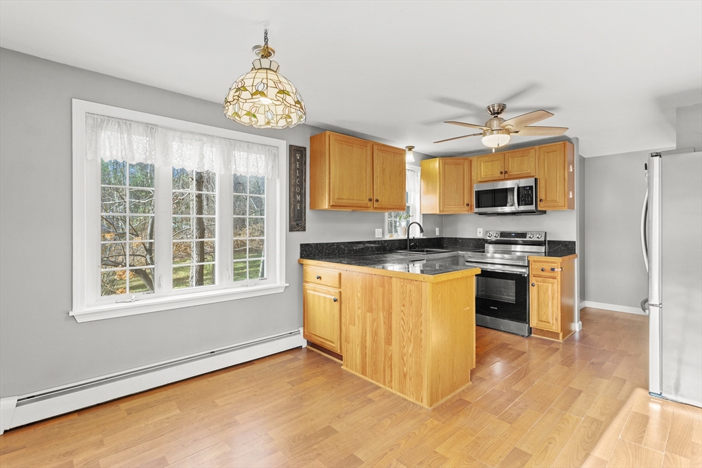 5 A Homestead Drive, Unit A Derry, NH 03038 - Photo 4 of 26 a kitchen with granite countertop a stove a sink a window and stainless steel appliances