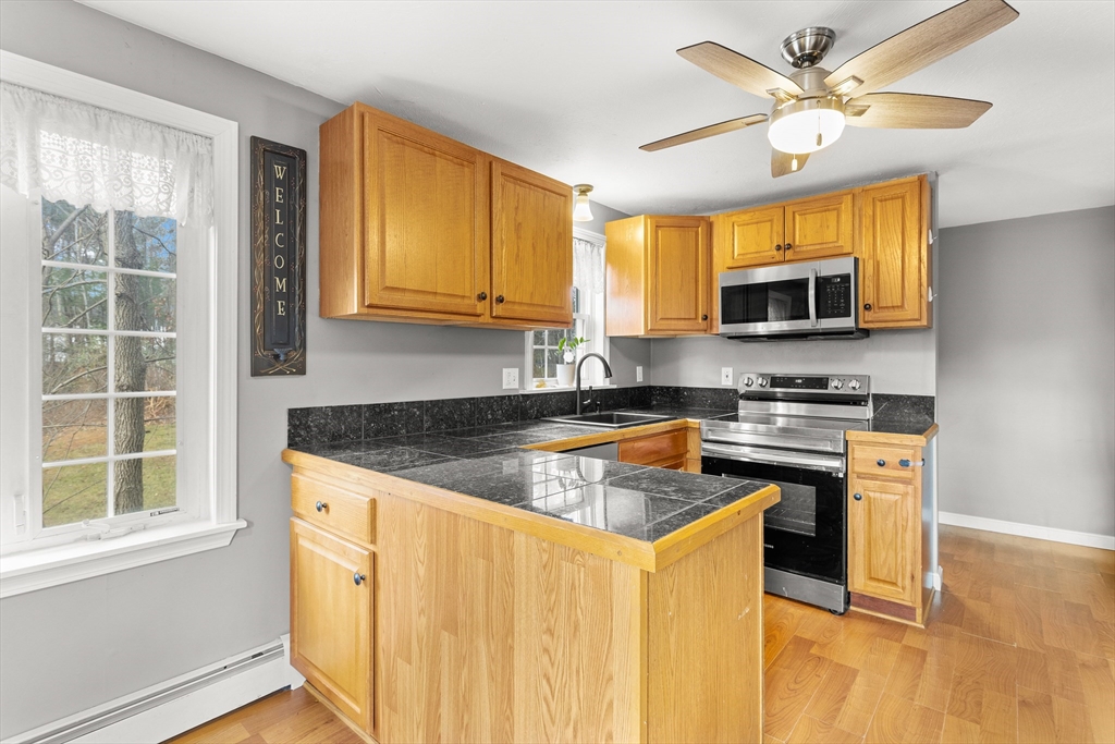 5 A Homestead Drive, Unit A Derry, NH 03038 - Photo 5 of 26 a kitchen with stainless steel appliances granite countertop a stove a sink and a microwave