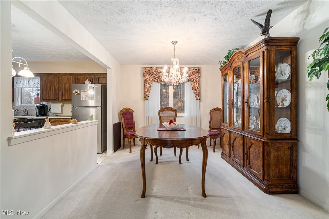 7353 Ames Road Cleveland, OH 44129 - Photo 14 of 45 Dining space with a textured ceiling, light colored carpet, baseboards, and an inviting chandelier