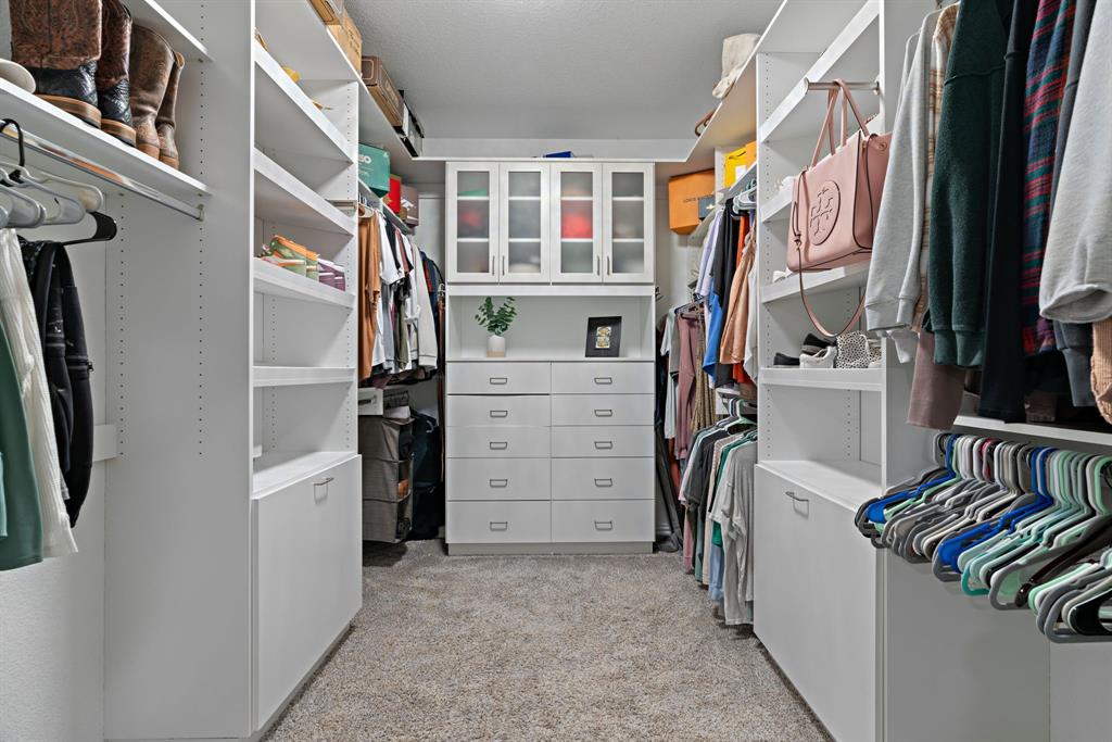 3112 Kingsgarden Road Denton, TX 76207 - Photo 31 of 38 Walk-in closet featuring built-in white cabinetry, multiple hanging rods, varied shelving, integrated drawers, and frosted glass cabinet doors