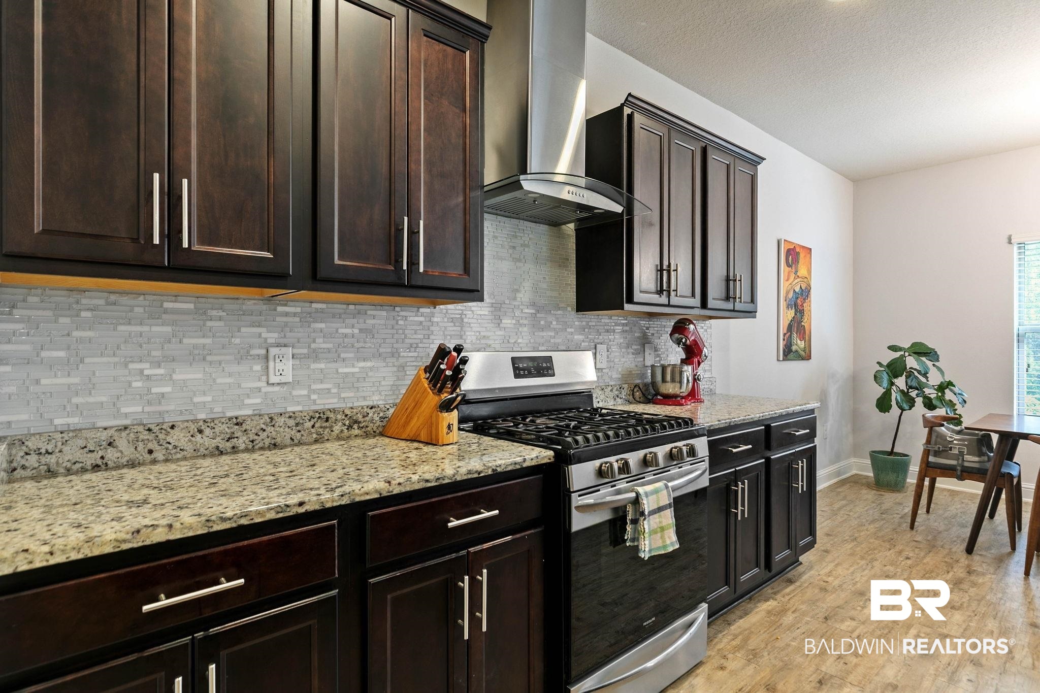 31350 Hoot Owl Road Daphne, AL 36527 - Photo 17 of 94 Kitchen with stainless steel range with gas stovetop, light stone counters, dark wood finish cabinets, backsplash, and a textured ceiling