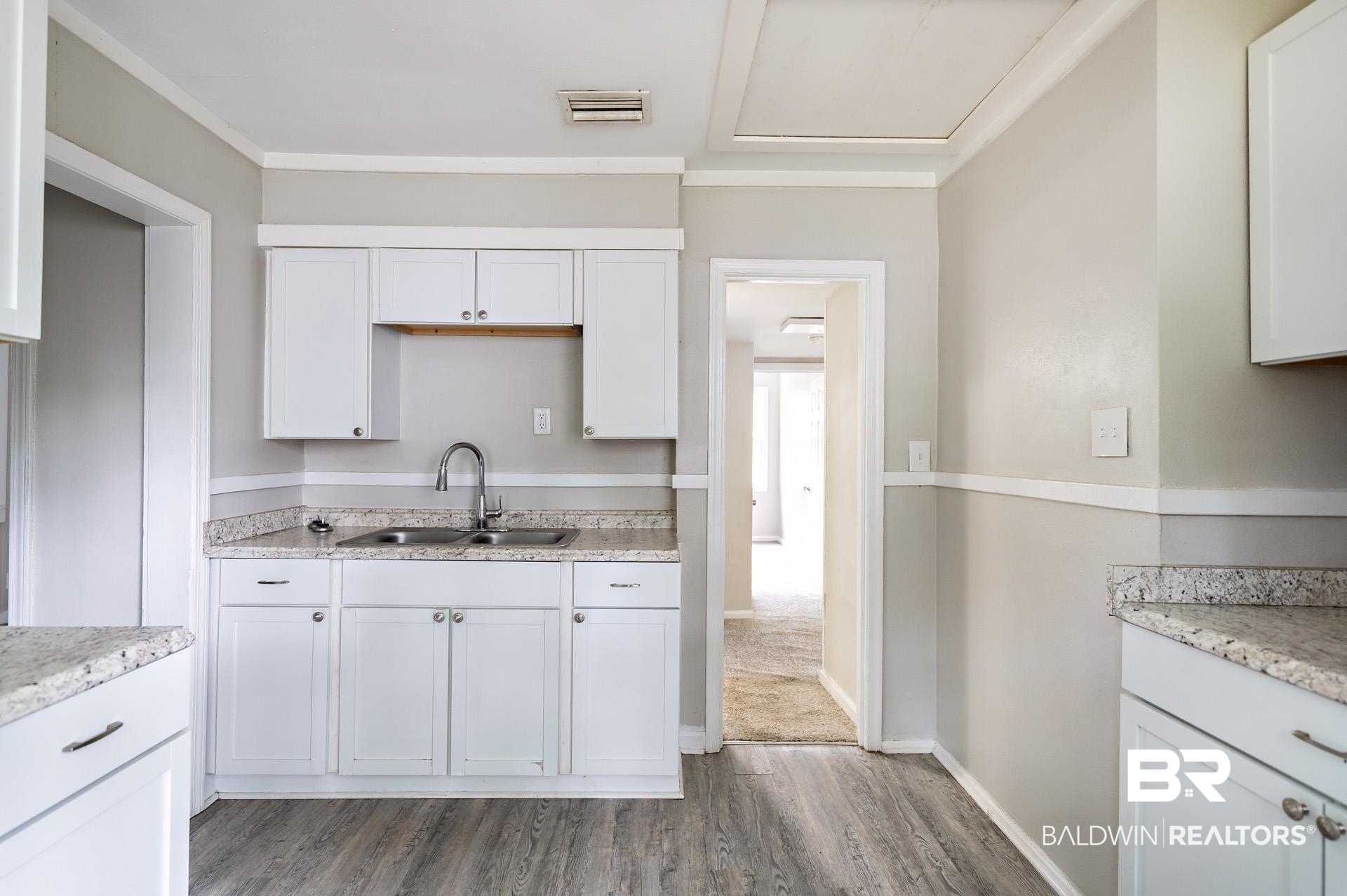 1869 Mott Drive West Mobile, AL 36617 - Photo 11 of 34 Kitchen featuring baseboards, a sink, visible vents, white cabinets, and wood finished floors