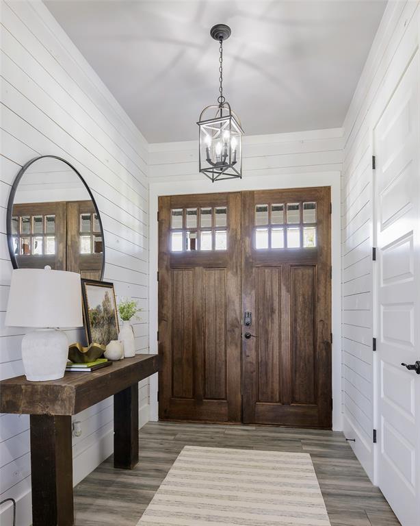 12345 Flow Road Krum, TX 76249 - Photo 12 of 38 Entryway with wood finished floors, wood walls, and a chandelier