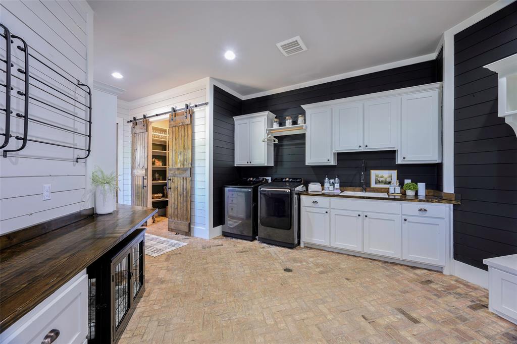12345 Flow Road Krum, TX 76249 - Photo 14 of 38 Kitchen with independent washer and dryer, a barn door, brick floor, a sink, and visible vents