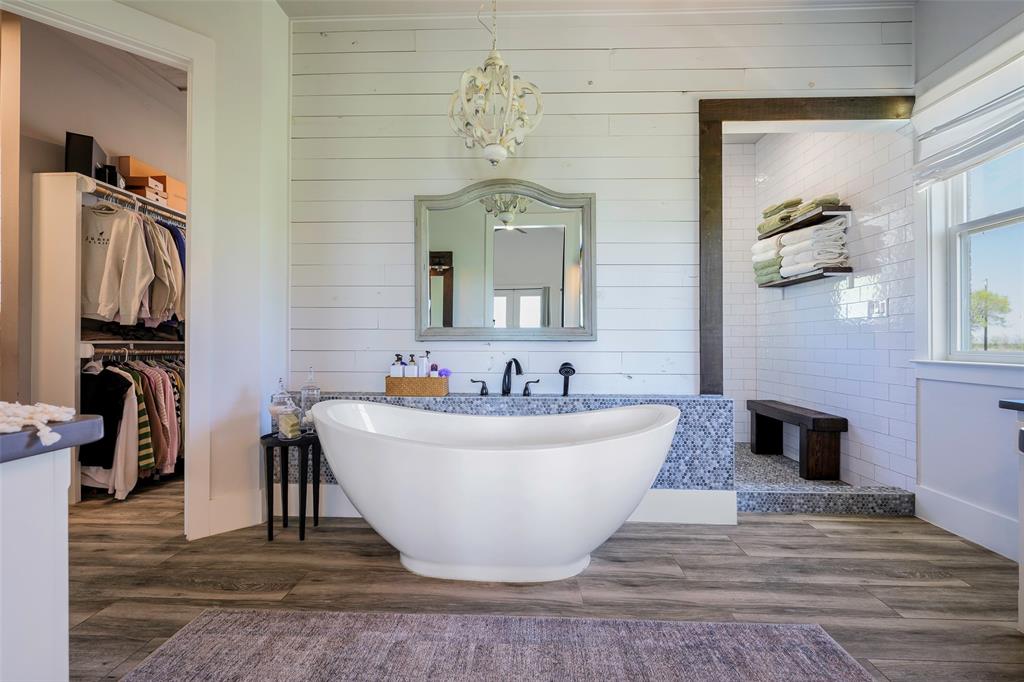 12345 Flow Road Krum, TX 76249 - Photo 17 of 38 Bathroom with a notable chandelier, a walk in closet, a soaking tub, and wood finished floors