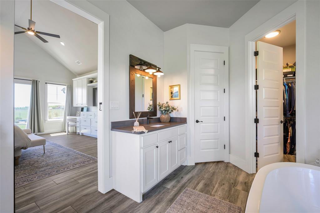 12345 Flow Road Krum, TX 76249 - Photo 19 of 38 Ensuite bathroom with ceiling fan, baseboards, wood finished floors, vanity, and a freestanding bath