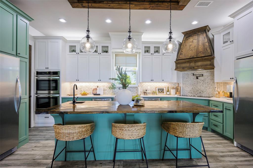 12345 Flow Road Krum, TX 76249 - Photo 8 of 38 Kitchen featuring stainless steel appliances, green cabinets, custom exhaust hood, visible vents, and an island with sink