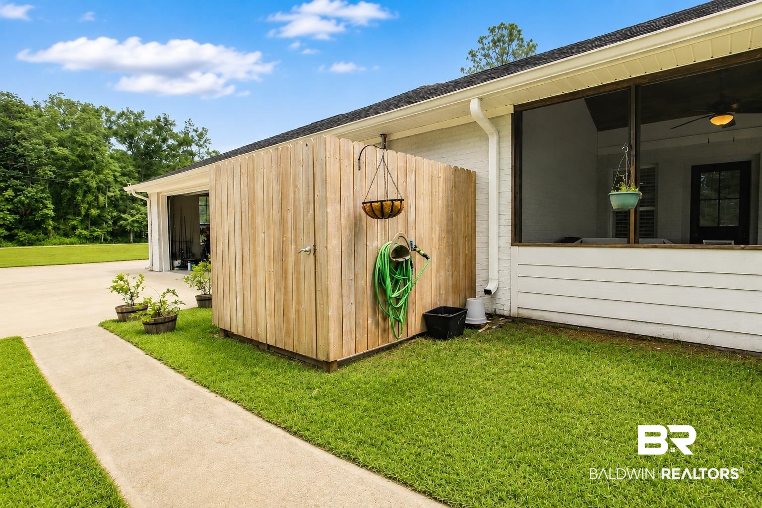 9825 Wolf Creek Ridge Elberta, AL 36530 - Photo 61 of 76 Expansive green lawn alongside a concrete pathway, leading to a screened porch with a dark-framed door and a built-in ceiling fan