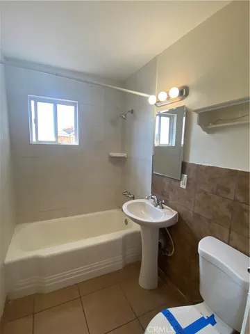 a bathroom with a sink a toilet a mirror and bathtub
