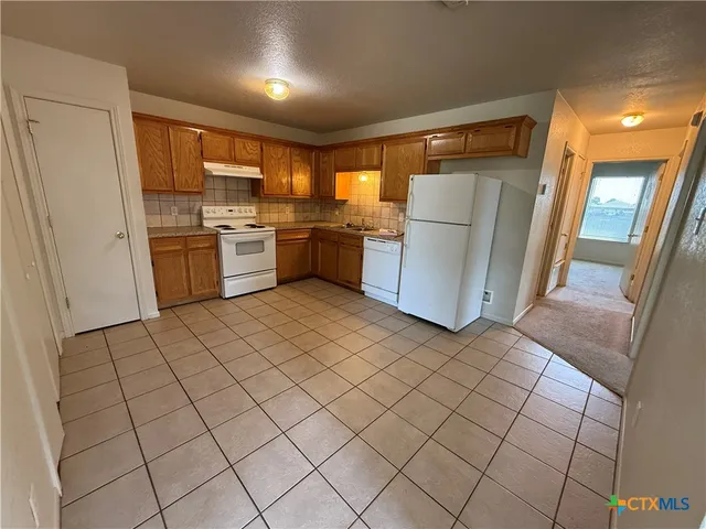 a kitchen with a refrigerator sink and cabinets