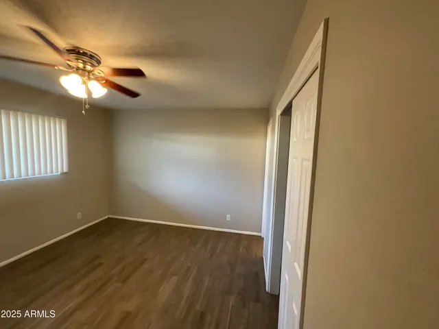 an empty room with wooden floor fan and windows