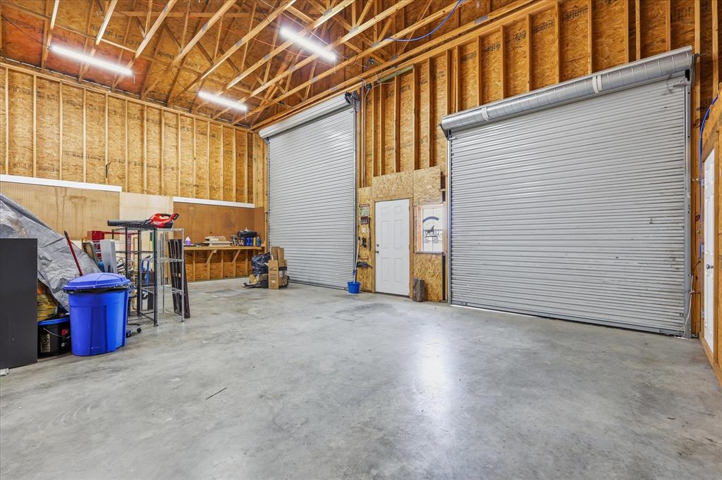 110 Highview Road Ennis, TX 75119 - Photo 26 of 40 Spacious utility building featuring two roll-up doors, exposed wood framing, concrete flooring, and overhead strip lighting