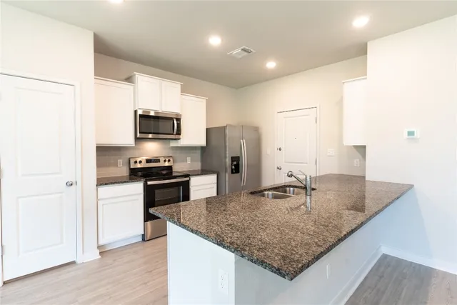 a kitchen with stainless steel appliances granite countertop a sink refrigerator and microwave