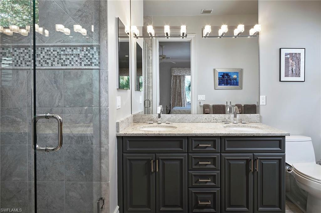 1626 Chinaberry Way Naples, FL 34105 - Photo 18 of 35 a bathroom with a granite countertop sink a large mirror and a shower