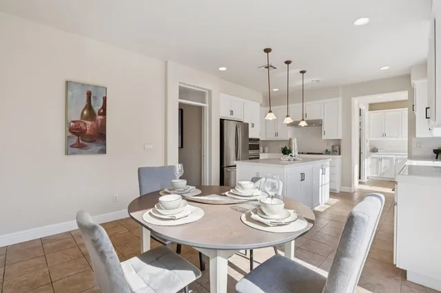 a kitchen with kitchen island stainless steel appliances a stove a refrigerator and white cabinets