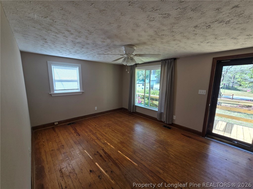 219 East Clinton Street Autryville, NC 28318 - Photo 2 of 32 an empty room with wooden floor and windows