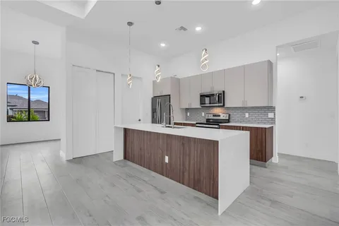 a kitchen with granite countertop a refrigerator stove top oven and cabinets