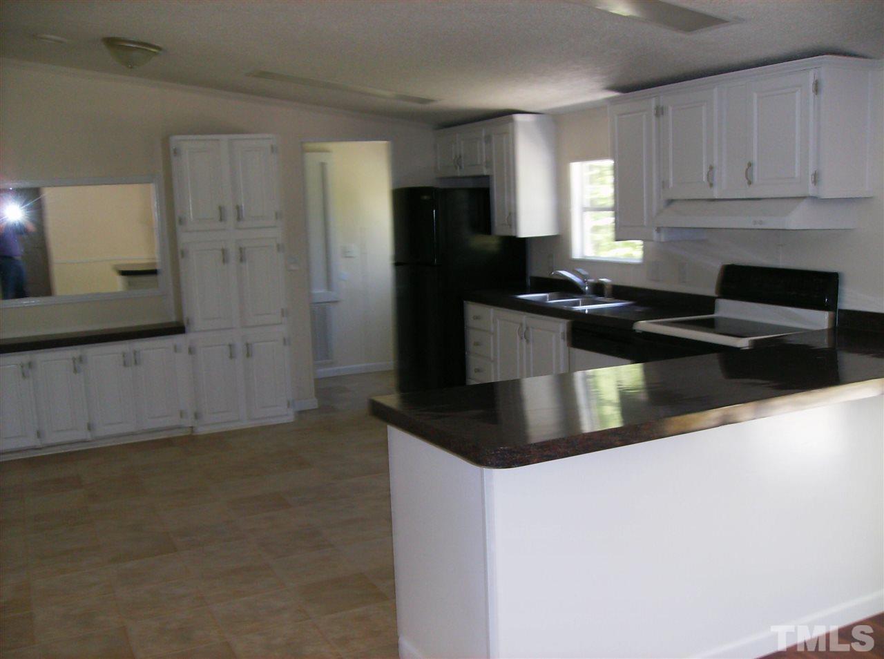 1077 Harris Mill Road Rougemont, NC 27572 - Photo 4 of 9 a kitchen with granite countertop a refrigerator sink and cabinets