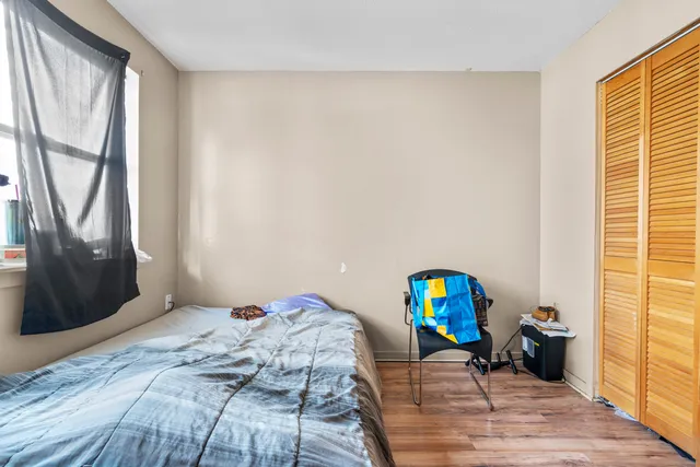 a bedroom with a bed a mirror on the dresser and a window