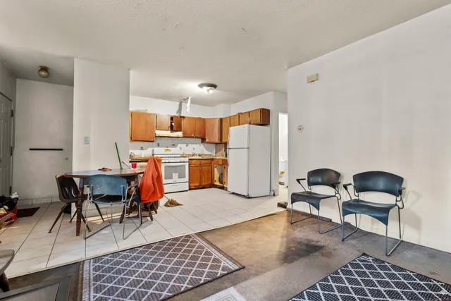 a living room with furniture a refrigerator and chairs