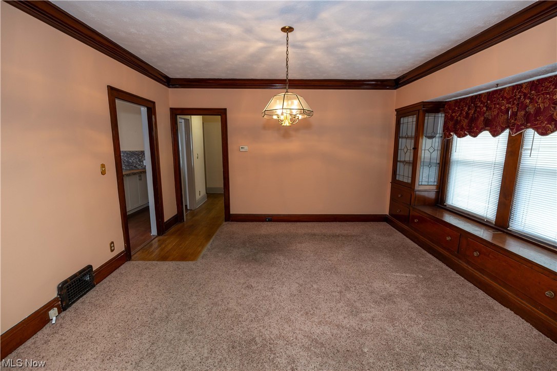 10105 Unity Avenue Cleveland, OH 44111 - Photo 6 of 35 Empty room featuring carpet floors, crown molding, and a chandelier