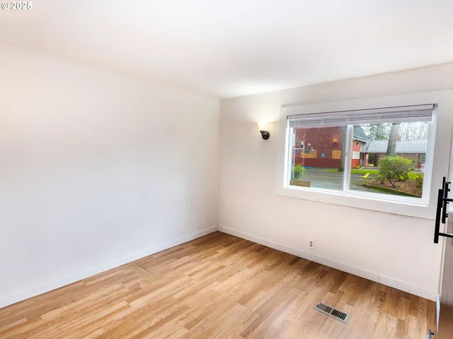 an empty room with wooden floor and a window