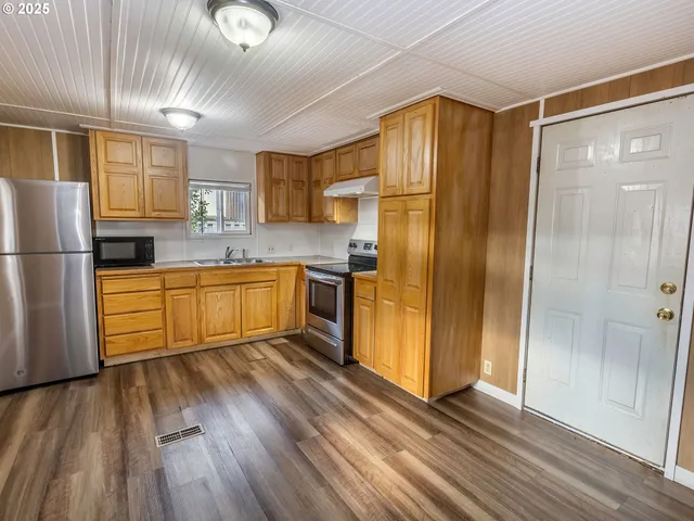 a kitchen with stainless steel appliances granite countertop a refrigerator a sink and a stove