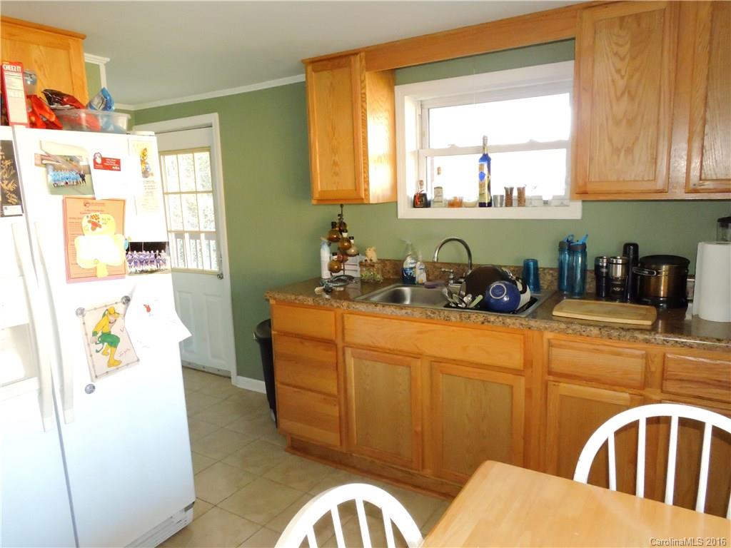 384 Scottdale Road Canton, NC 28716 - Photo 3 of 12 a kitchen with stainless steel appliances a refrigerator a sink a stove and a dining table with wooden floor