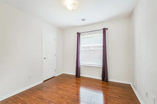 a view of empty room with wooden floor