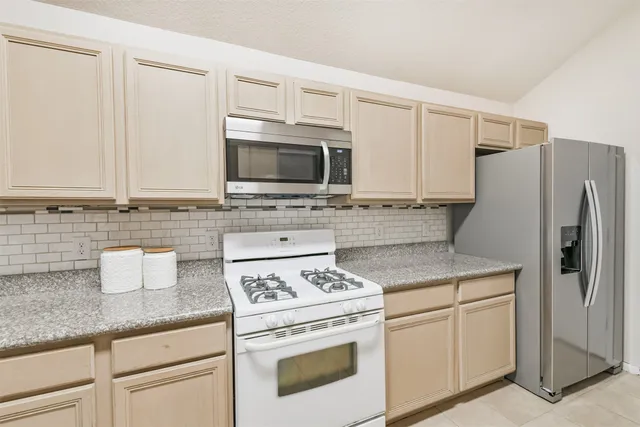 a kitchen with granite countertop a stove sink and refrigerator