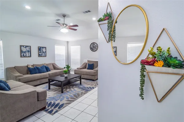 a living room with furniture a mirror and a fan