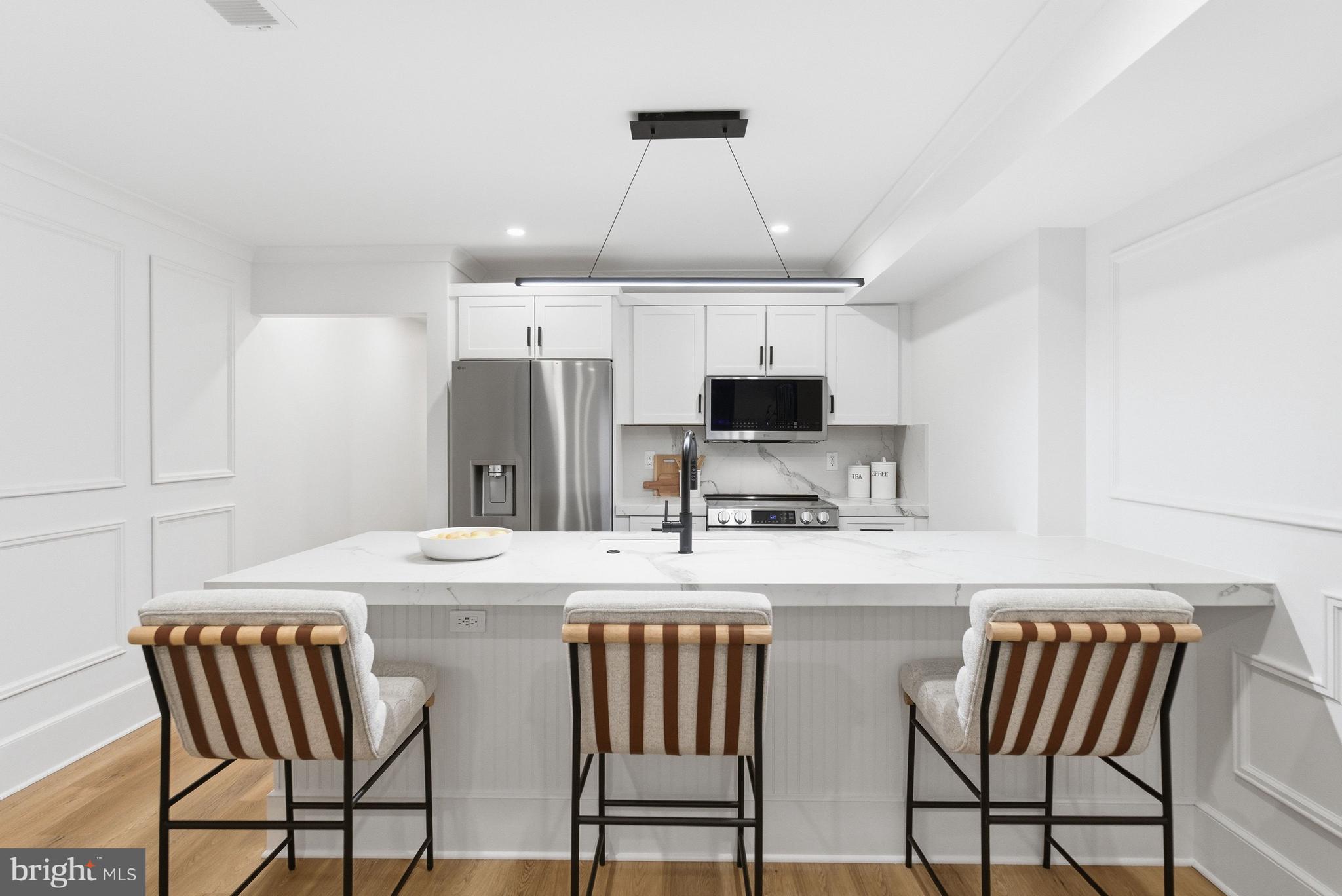 1816 Belmont Road Northwest Washington, DC 20009 - Photo 56 of 62 a kitchen with stainless steel appliances a table chairs and a refrigerator