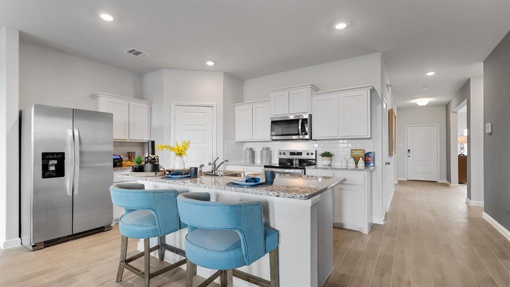 317 Potato Street Keene, TX 76059 - Photo 35 of 36 a kitchen with stainless steel appliances granite countertop a refrigerator a stove top oven a sink dishwasher and white cabinets with wooden floor