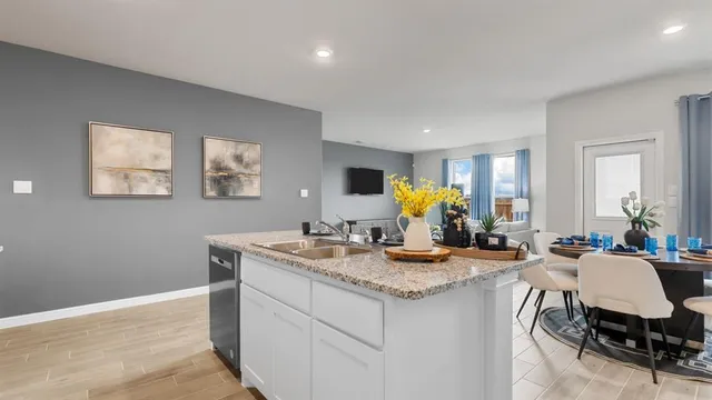 a kitchen with stainless steel appliances granite countertop a refrigerator a stove top oven a sink dishwasher and white cabinets with wooden floor