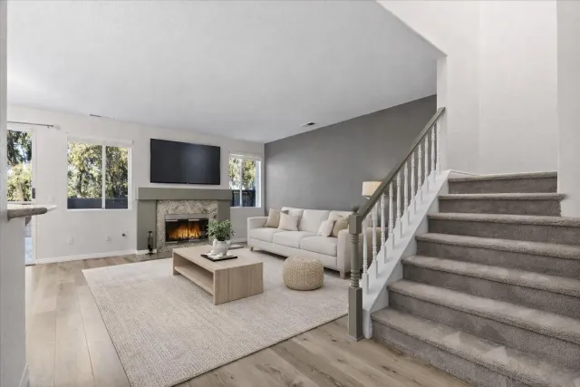 a view of a livingroom with wooden floor fireplace and windows