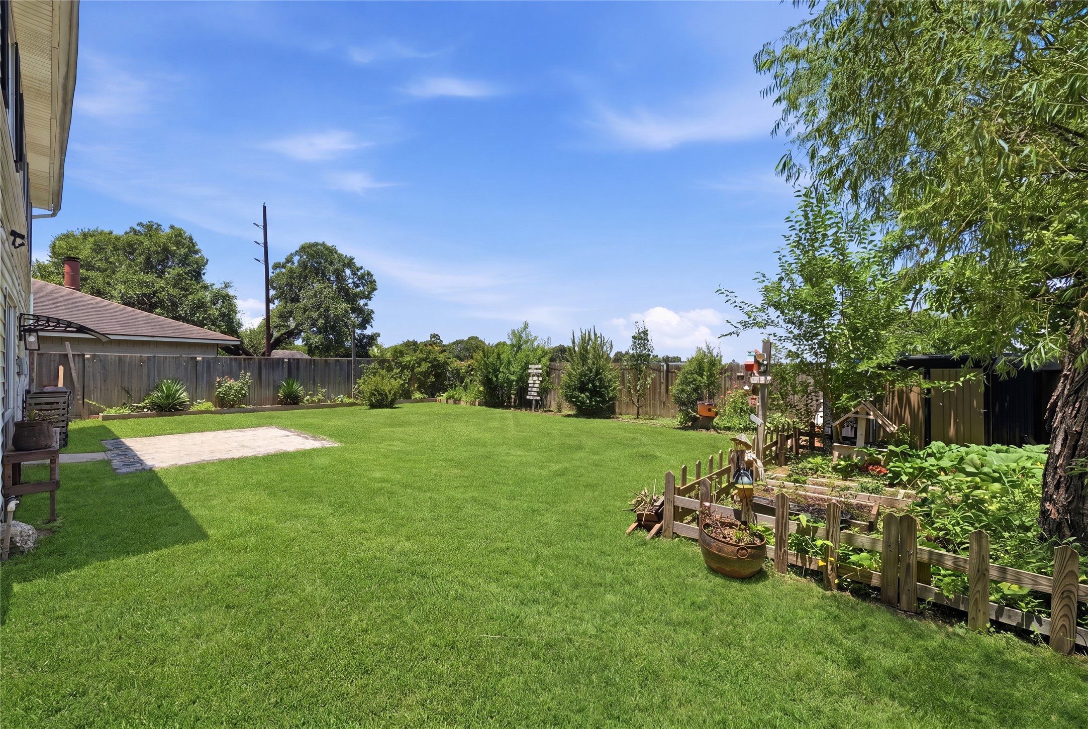 4718 Temple Bell Drive Spring, TX 77388 - Photo 40 of 50 This photo showcases a spacious backyard with well-maintained grass, a small patio area, and a fenced vegetable garden. The yard is bordered by a wooden fence, offering privacy and a serene outdoor space.