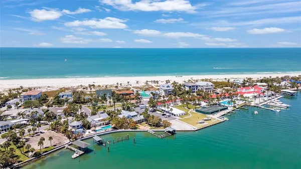 an aerial view of ocean and residential houses with outdoor space