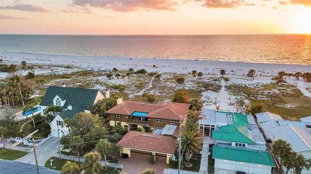 an aerial view of ocean and residential houses with outdoor space