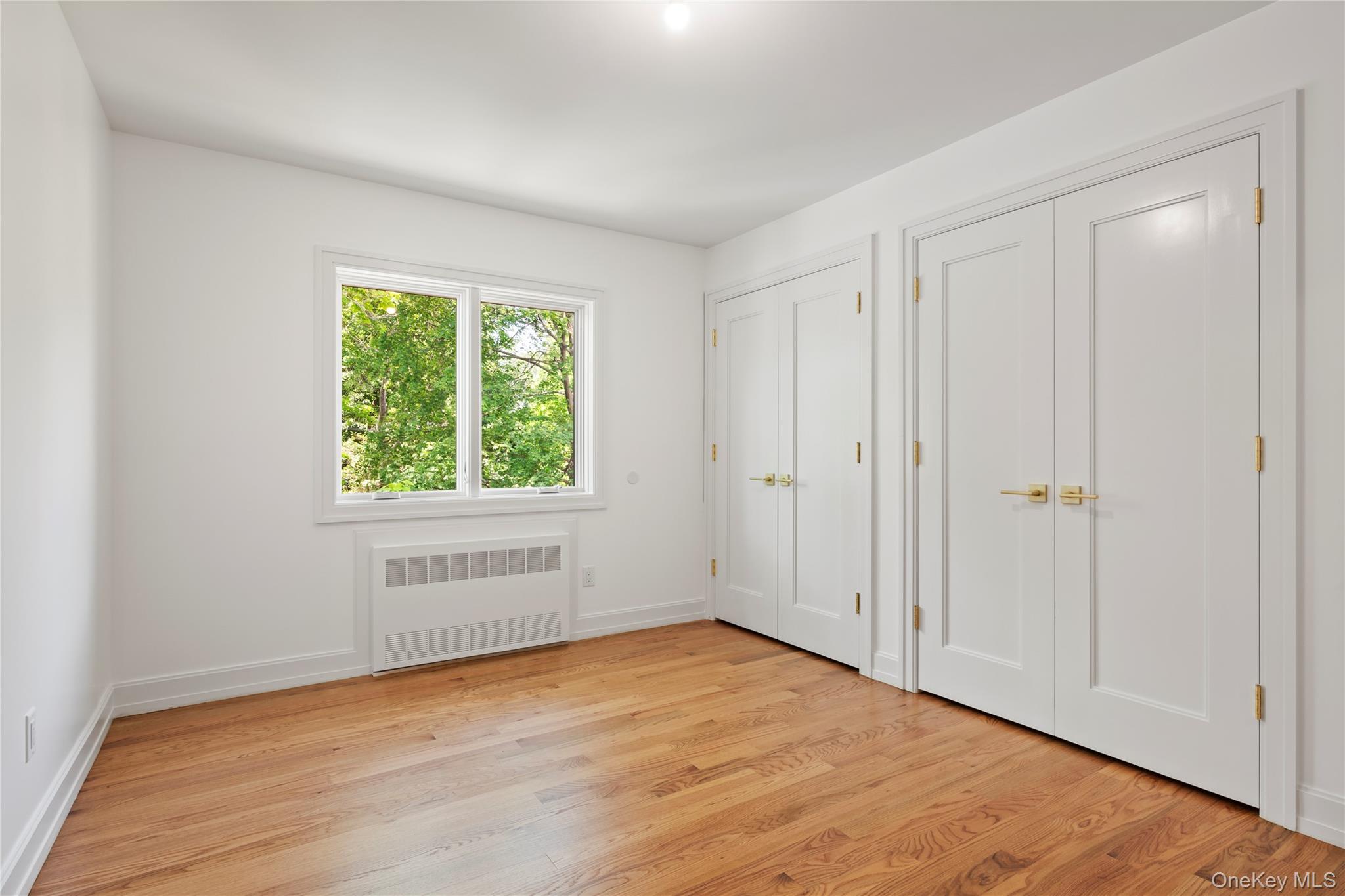 128 Union Road, Unit 201 Spring Valley, NY 10977 - Photo 34 of 48 Unfurnished bedroom featuring two closets, radiator, and light wood finished floors