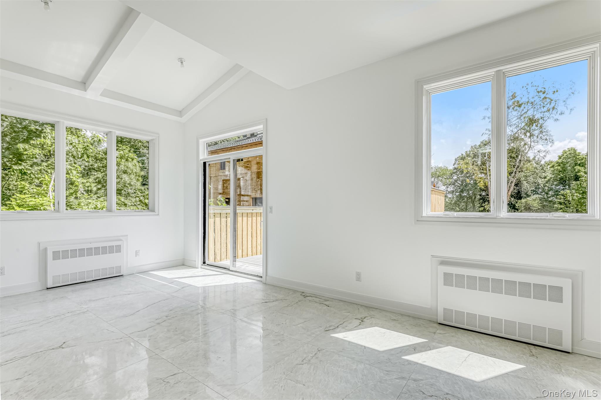 128 Union Road, Unit 201 Spring Valley, NY 10977 - Photo 9 of 48 Spare room featuring radiator heating unit, light marble finish flooring, and lofted ceiling