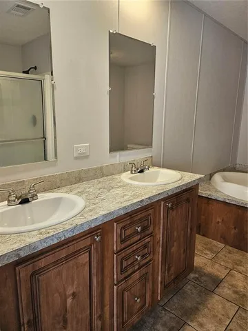 a bathroom with a granite countertop double vanity sink and a mirror