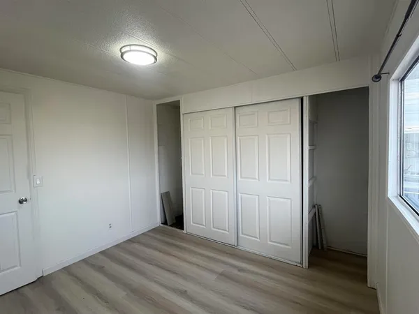 an empty room with wooden floor and closet area