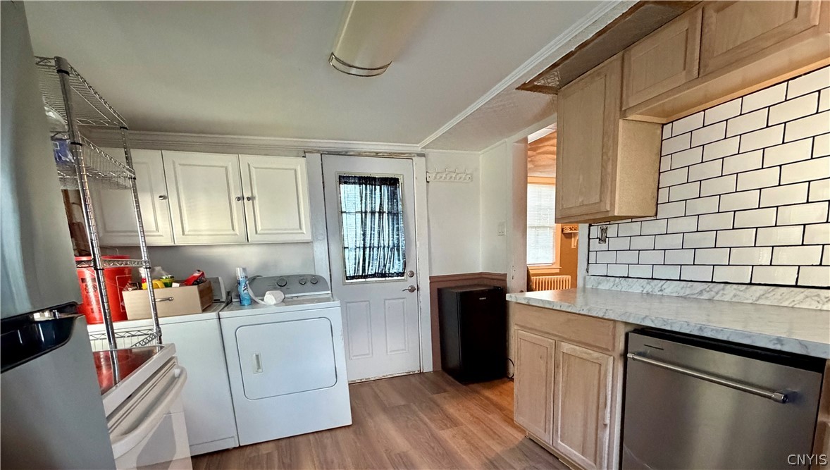 35 Paris Road New Hartford, NY 13413 - Photo 5 of 17 Kitchen view facing the rear entrance door, showcasing a newly installed subway tile backsplash, updated cabinetry, and new dishwasher. Convenient first-floor laundry with washer and dryer included.