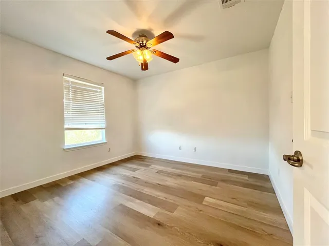 an empty room with a window and a ceiling fan
