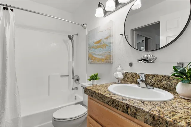 a bathroom with a granite countertop sink toilet a mirror and shower