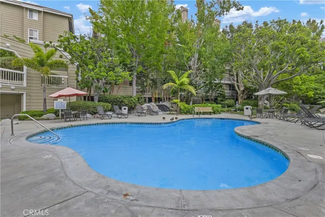 a view of a swimming pool with some potted plants and large trees