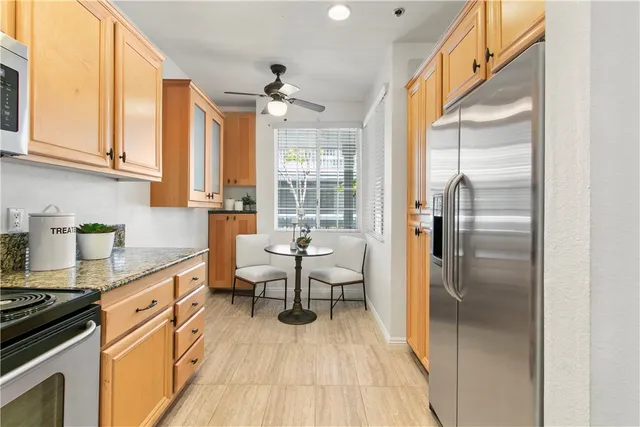 a kitchen with stainless steel appliances granite countertop a refrigerator a sink dishwasher a stove and white countertops with wooden floor